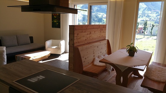 Blick von der Küche (mit Dunstabzug) in Richtung Esstisch und Couch, mit Aublick auf die Umgebung in Matrei in Osttirol