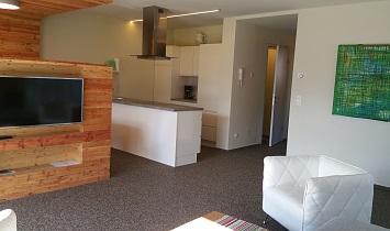 View from the couch of the LCD television and to the contemporary kitchen 