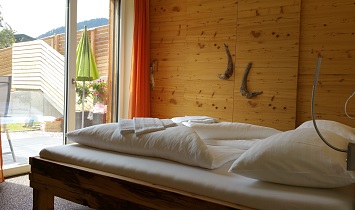 Doppelbett mit traditionellen Holzelementen, zudem herrliche Aussicht in die Tiroler Bergwelt