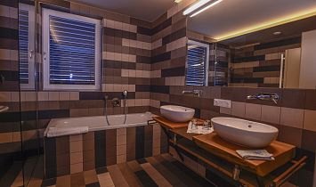 Komfortables und modernes Badezimmer mit Badewanne, Dusche, zwei Waschbecken und Handtuchtrockner
