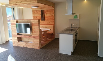 Offener Wohnraum mit gemütlichen Essbereich mit traditionellen Holzelement, der Essbereich schließt direkt an die voll ausgestattete Küche an